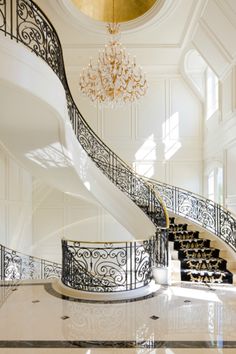 an elegant staircase with chandelier and marble flooring in a large white room