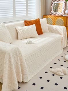 a living room with white couches and black and white checkered floor tiles on the floor