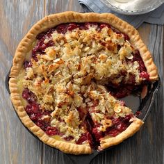 a pie sitting on top of a wooden table next to a plate with a slice missing