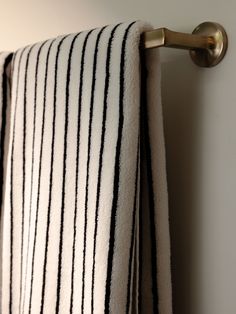 a towel hanging on the side of a white wall next to a metal hook with black and white stripes