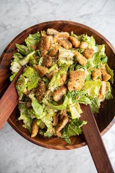 a wooden bowl filled with lettuce and chicken