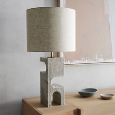 a table lamp sitting on top of a wooden table next to a bowl and plate