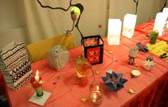 a red table topped with lots of different types of decorations and candles on top of it