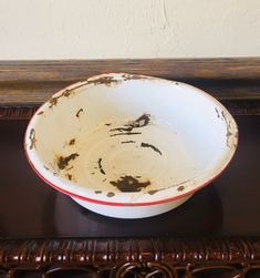 a white bowl sitting on top of a wooden table next to a brown and white wall