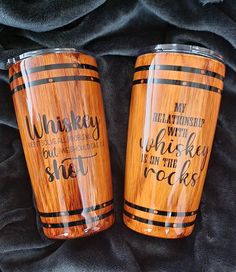 two wooden tumblers sitting on top of a black blanket next to eachother