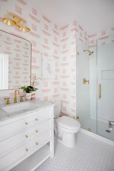 a white bathroom with pink and gold wallpaper