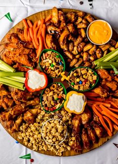 a platter filled with chicken wings, carrots, celery and other foods