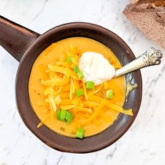 a brown bowl filled with soup and cheese on top of a white marble countertop