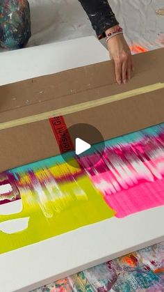 someone is painting on a large box with watercolors and tape in the background