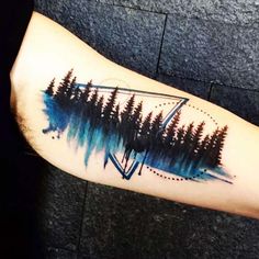 a person with a tattoo on their arm that has trees in the background and an arrow at the bottom