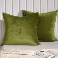 two green pillows sitting on top of a bed