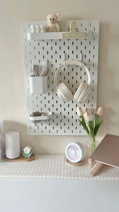 a white pegboard mounted to the side of a wall next to a vase with flowers