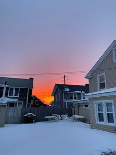 the sun is setting behind some houses