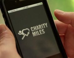 a person holding a smart phone with charity miles sticker on the screen in their hand