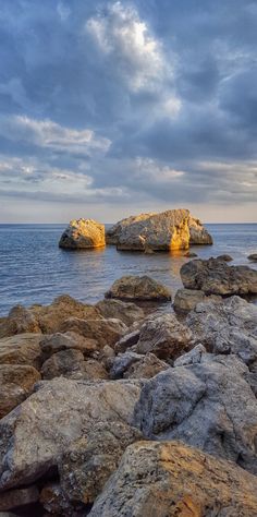 some rocks and water under a cloudy sky