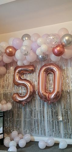 balloons and streamers decorate the entrance to a 50th birthday party in pink, silver and gold