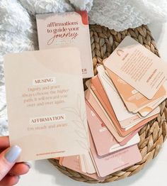 a basket filled with lots of pink and white cards next to a hand holding a paper