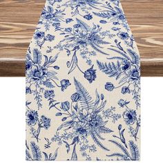 an ironing board with blue flowers and leaves on it, next to a wooden table