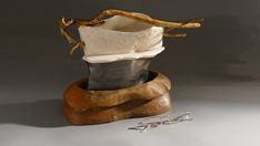 a pair of scissors sitting on top of a wooden bowl next to a piece of driftwood