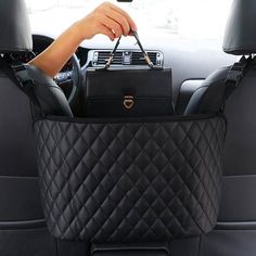 a woman holding a black purse in the back seat of a car with her hand on it