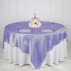 a pink table cloth with two white plates and a tiara on top is shown