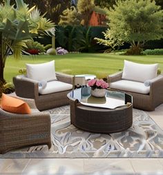 an outdoor living area with wicker furniture and flowers on the table in the center