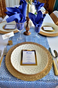 the table is set with blue and gold place settings, silverware, and napkins