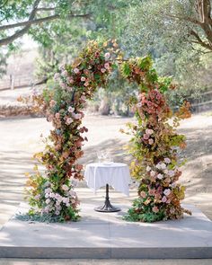 an outdoor table set up with flowers and greenery