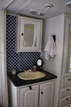 a bathroom with white cabinets and black counter top next to a mirror on the wall