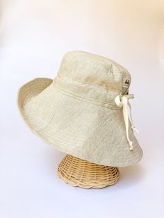 "A sun hat for beach days and summer fun. This sun hat for women has a nice wide brim to protect your whole face and even your neck and chest. A drawstring around the head keeps the hat fitting snug. Easy to bring along in your bag, folds up easy. This hat is made from a medium weight homespun linen and cotton blend fabric in a neutral beige color. Inside liner is white cotton. I used a stiff interfacing for brim to keep it's shape. Brim measures 4.5\" Crown depth is 3.5\". Contact me for custom Adjustable Solid Color Sun Hat For Beach Season, Lightweight Solid Color Sun Hat For Summer, Lightweight Solid Color Summer Sun Hat, Summer Sun Hat With Curved Brim For Sunbathing, Cotton Brimmed Hat For Beach Season, Lightweight Sun Hat With Flat Brim, Lightweight Beige Sun Hat For Vacation, Cotton Summer Hat For Vacation, Adjustable Flat Brim Bucket Hat For Beach Season