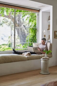 a man sitting on a couch in front of a window with a laptop computer next to him