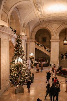 people are walking around in the lobby of a building with christmas decorations on the walls