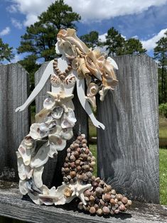 a statue made out of seashells on top of a wooden fence