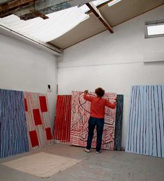 a person standing in front of paintings on the wall and painting them with red, white, and blue colors