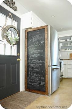 a chalkboard with writing on it is in front of a black door and white cabinets