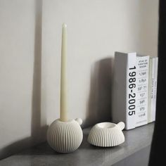 two white candles sitting on top of a shelf