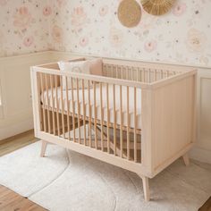 a baby crib in a room with floral wallpaper