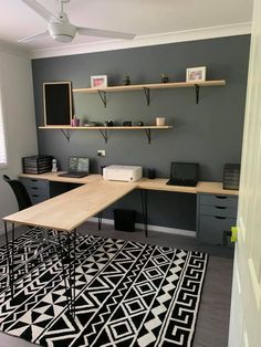 a room with two desks, shelves and a rug on the floor in front of it