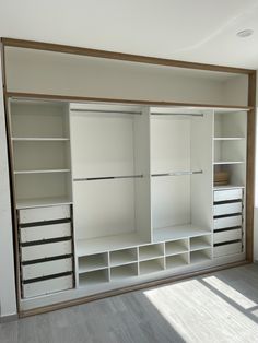 an empty room with white shelves and drawers on the wall, in front of a window