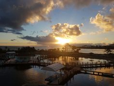 the sun is setting over some docks and water