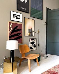 a living room with pictures on the wall and a chair in front of a lamp