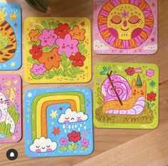 four square coasters with colorful designs on them and a plant in the middle one