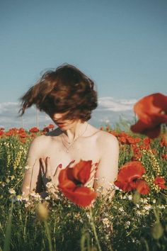 a woman sitting in a field of flowers with her hand on her chest and eyes closed