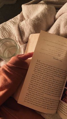 someone is reading a book in bed with their hand on top of the open book