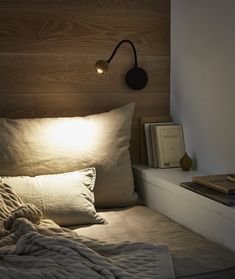 a bed that has some pillows on it and a lamp next to the headboard