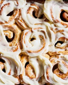 cinnamon rolls with icing sitting on top of each other in a baking pan, ready to be eaten