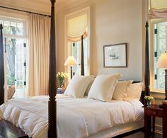 a bed with white sheets and pillows in a bedroom next to two lamps on either side of the bed