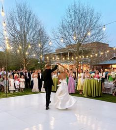 a bride and groom dancing on the dance floor in front of an outdoor wedding reception