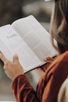 a woman is holding an open book with the word provers on it in her hands