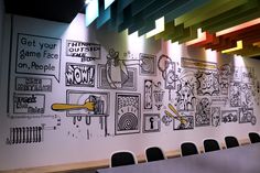 a drawing on the side of a wall next to a long table with black chairs